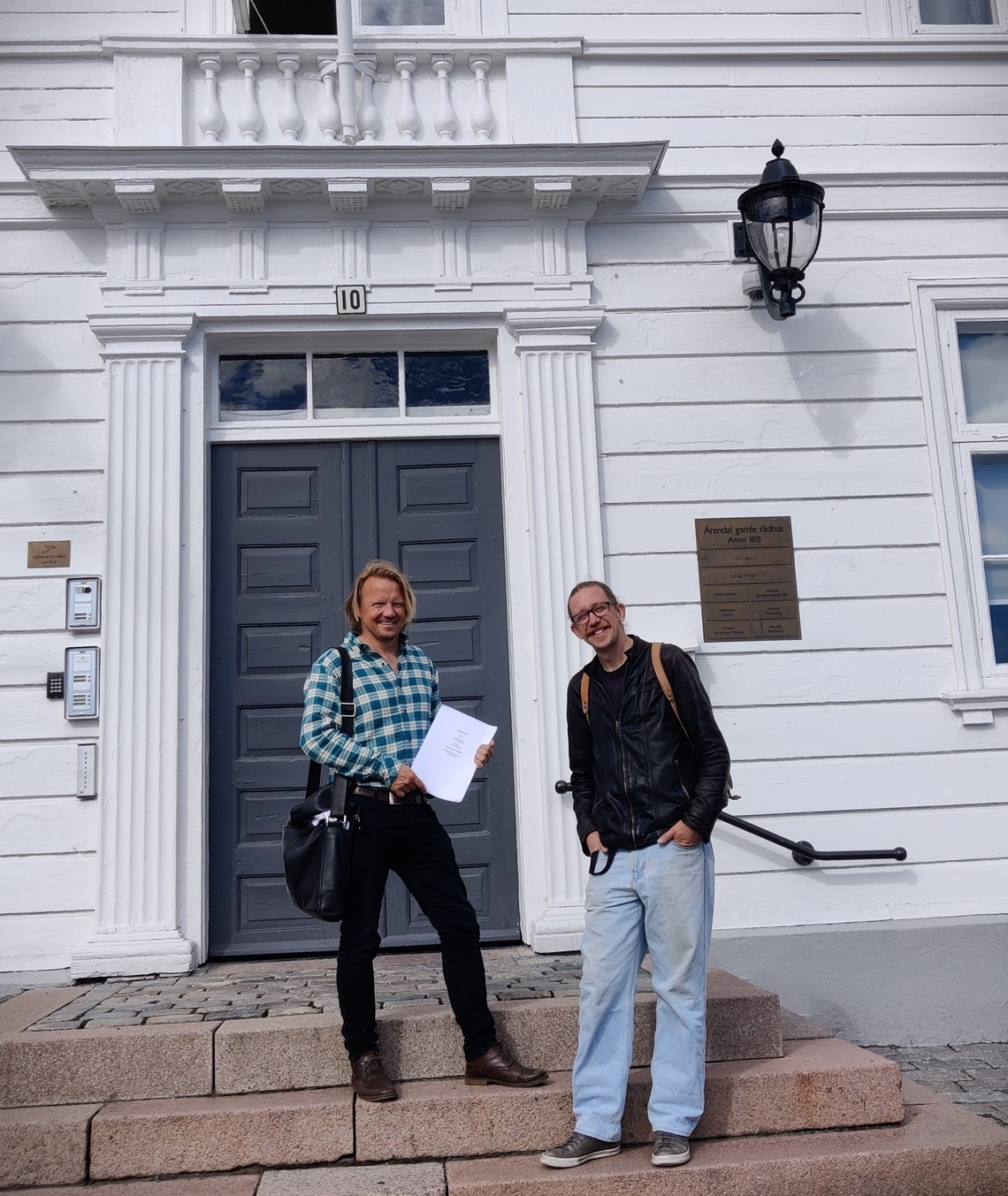 Bilde: Peder Horgen og Martin Woll Godal med signert kjøpskontrakt utenfor Arendal Eiendoms kontorer på Arendal gamle rådhus.